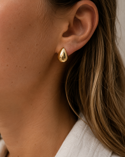 18K gold plated druppel oorbellen gedragen door een model. Elegante gouden statement oorbellen met een moderne, luxe uitstraling.
