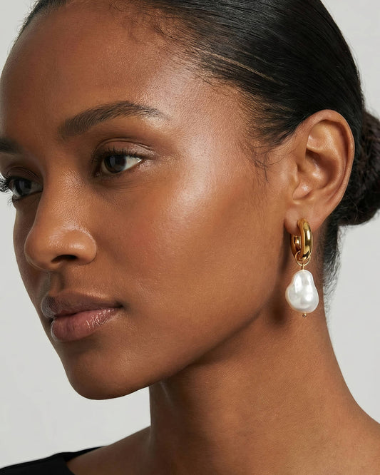 18K gold plated creool oorbellen met witte hanger gedragen door een model. Stijlvolle gouden oorbellen met een elegante en tijdloze uitstraling.