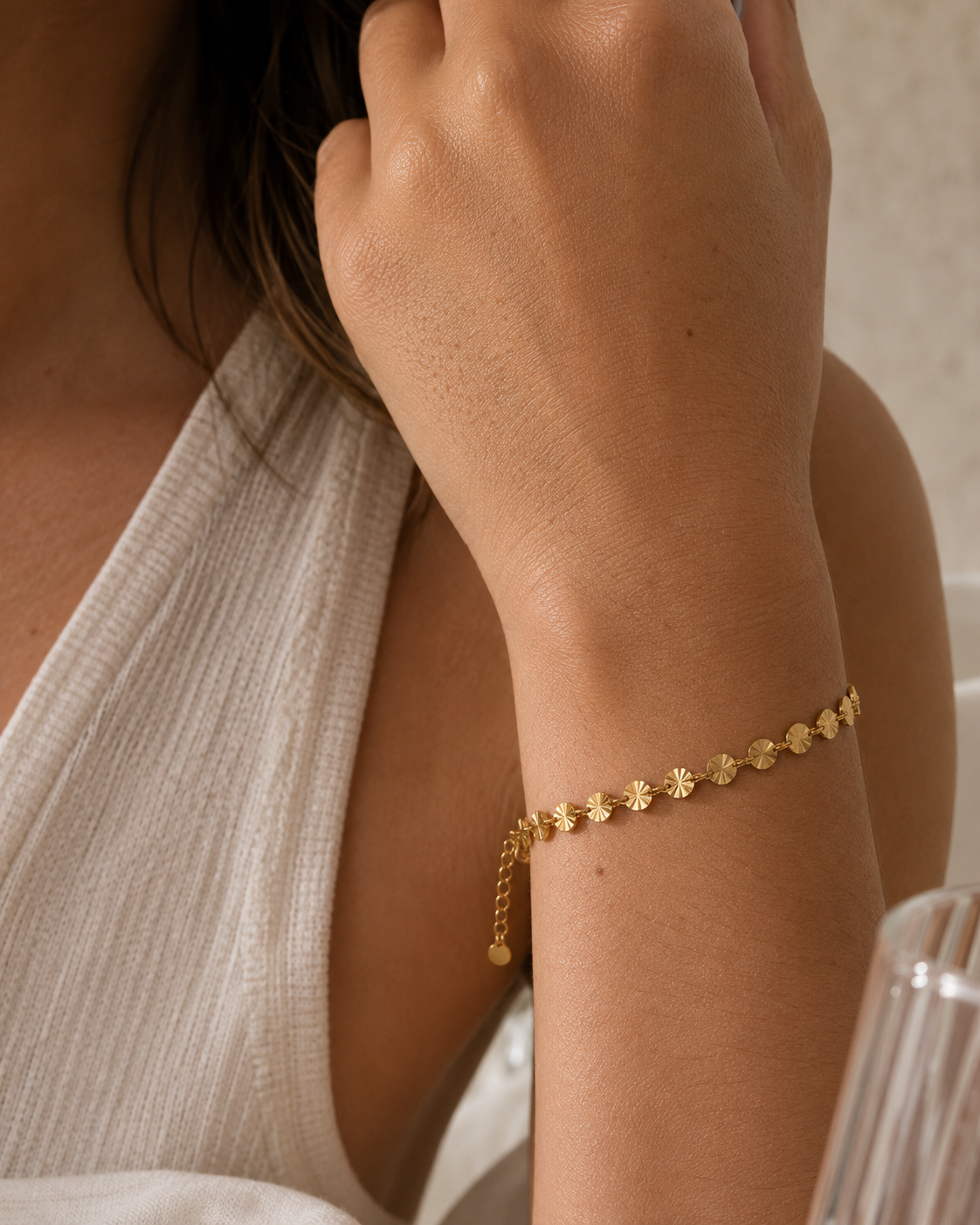 18K gold plated disc armband met ronde gouden schijfjes gedragen om de pols van een model. Elegante gouden damesarmband met een verfijnde en moderne uitstraling.