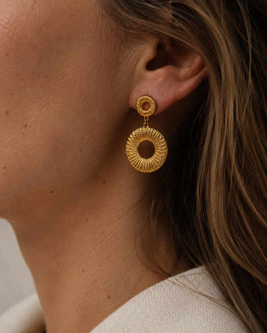 18K gold plated oorbellen met cirkelstructuur gedragen door een model. Statement gouden oorbellen met een verfijnde textuur en elegante uitstraling.