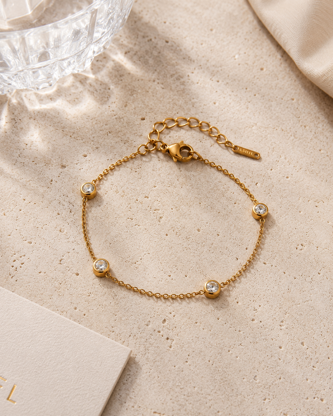 Gouden armband met ronde zirkonia steentjes stijlvol gepresenteerd op een beige natuurstenen tafel