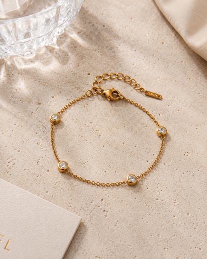 Gouden armband met ronde zirkonia steentjes stijlvol gepresenteerd op een beige natuurstenen tafel