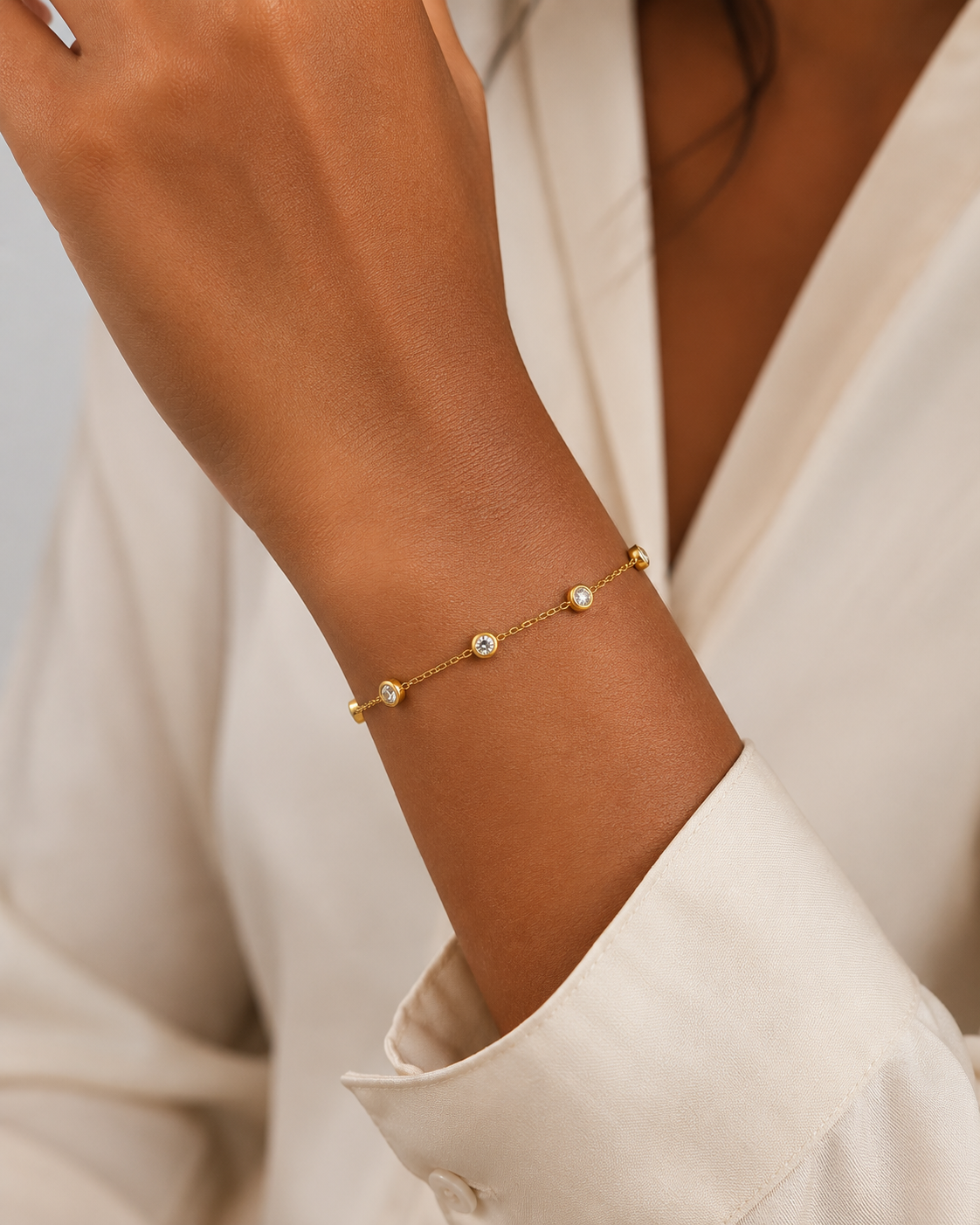 Model draagt gouden armband met ronde zirkonia steentjes om de pols