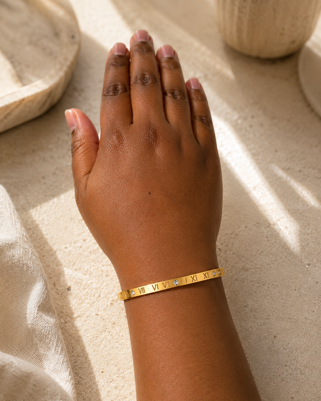 Model draagt goudkleurige armband met Romeinse cijfers en vier zirkonia stenen.