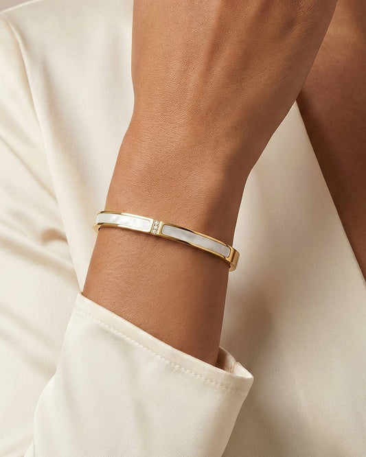 Model draagt goudkleurige armband met parelmoer inleg en drie zirkonia steentjes