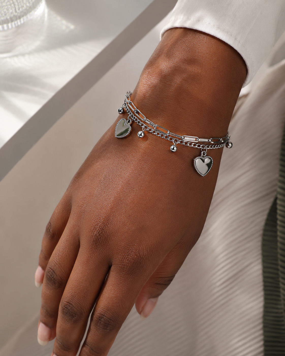 Model draagt zilveren schakelarmband met hartbedels om de pols