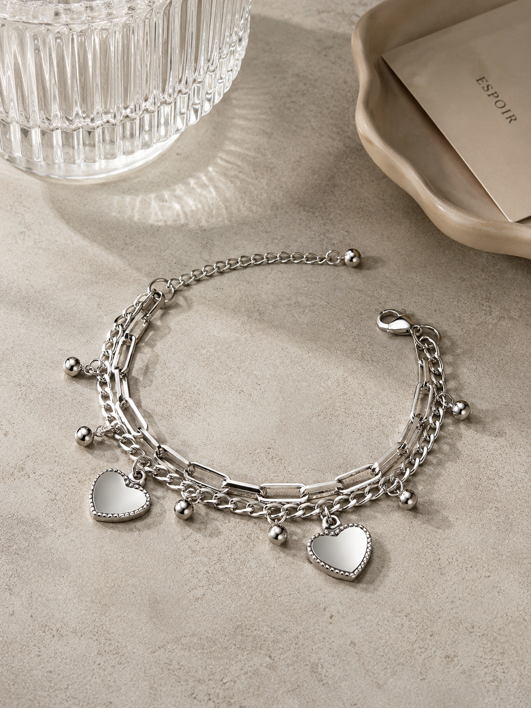 Zilveren schakelarmband met hartbedels stijlvol gepresenteerd op een natuurstenen tafel
