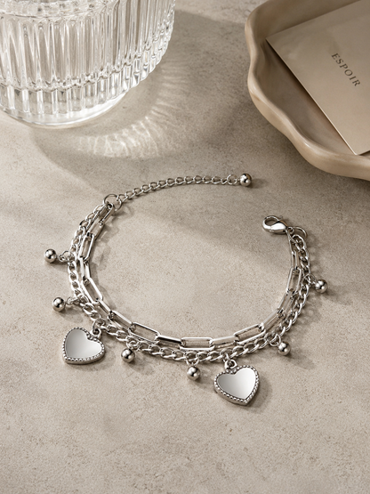 Zilveren schakelarmband met hartbedels stijlvol gepresenteerd op een natuurstenen tafel