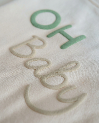 Close-up van OH Baby opdruk in groen en beige op zacht babyshirt van katoen